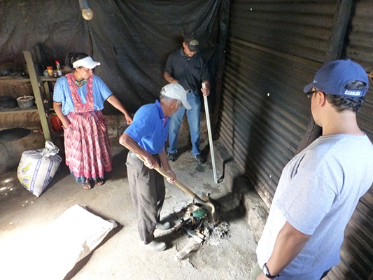 The stove recipient cleaning up the remains of a small fire that he previously used to cook with.