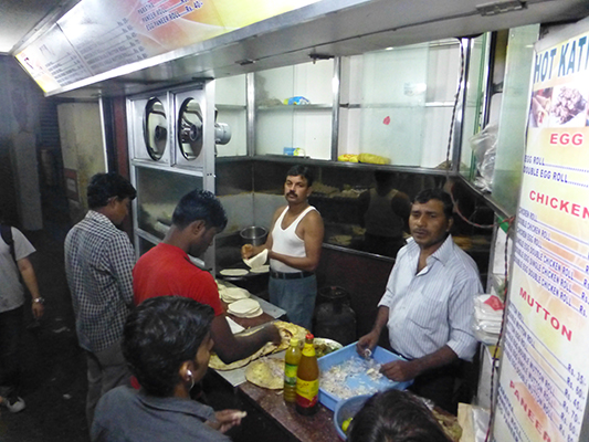 The master Kathi chefs. The youngest guy on the left rolled the dough into flat circles Then the guy in the back fried the dough and also cooked the fillings on the huge concave frying pan. Next the guy in red filled the fried wraps. The fella in the foreground took orders  and money, and then passed out the goods. Very efficient operation. 