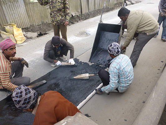 Laying the black top with wood trowels.