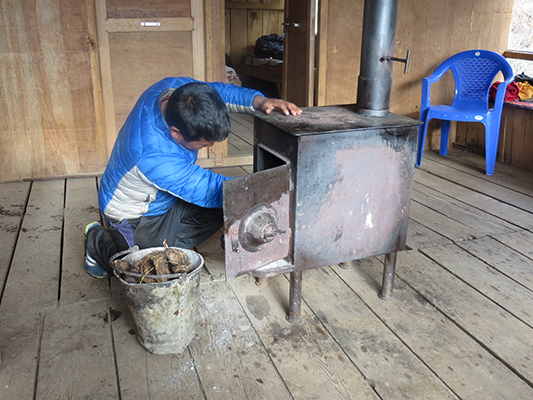Keeping warm by burning yak dung in the stove. 